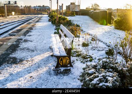 Royal Leamington Spa, Warwickshire, Großbritannien. 25. Januar 2021: Nach einem Tag Schneefall ist der Landkreis zu einer frostigen Winterlandschaft aufgewacht. Die Bahnsteige der Leamington Spa Station wurden gesalzen, sind aber immer noch rutschig und stellenweise sehr verschneit. Der Garten des Bahnhofs glitzert von Schnee, wie auch die charakteristischen Bänke der GWR (Great Western Railway). Kredit: Ryan Underwood / Alamy Live Nachrichten Stockfoto