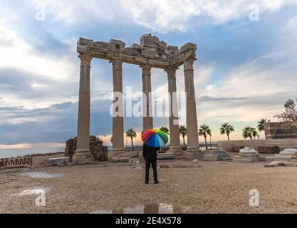 Ein Mann in schwarz gekleidet mit einem Regenbogenschirm steht vor dem Tempel des Apollo in der alten Stadtseite bei Rainy and Cloudy Day. Stockfoto