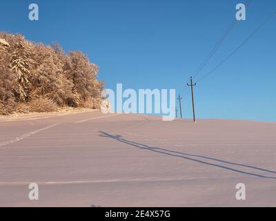 Schneeschuhwanderwege über ein schneebedecktes weißes Feld in Österreich Stockfoto