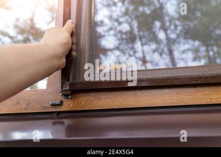 Close-up professionelle Arbeiter Hand Installation Fenster Moskito Insekt Fliegenschutz an Holzhaus Außenwand. Haushälterin Stockfoto