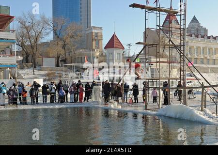 HARBIN, CHINA - 30 Januar, 2010: Touristen bewundern Harbin der Einheimischen einzutauchen in die Bohrung schneiden in eisigen Songhua Fluss während der berühmten, jährliche Harbin Ice Stockfoto