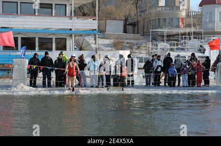 HARBIN, CHINA - 30 Januar, 2010: Touristen bewundern Harbin der Einheimischen einzutauchen in die Bohrung schneiden in eisigen Songhua Fluss während der berühmten, jährliche Harbin Ice Stockfoto