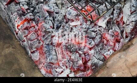 Natürliche Holzkohlen zum Grillen brennen, schwelen und glühen im Grill, für die Zubereitung von gegrillten Speisen. Verschwommener Hintergrund von schwelenden Charkohlen. Heiß e Stockfoto