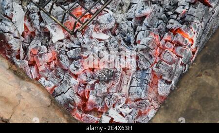 Natürliche Holzkohlen zum Grillen brennen, schwelen und glühen im Grill, für die Zubereitung von gegrillten Speisen. Verschwommener Hintergrund von schwelenden Charkohlen. Heiß e Stockfoto