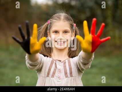 Happy Outdoor-Porträt des Kindes Mädchen mit Händen in Belgien Flagge Farben gemalt. Kreativ Stockfoto