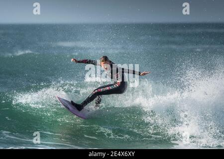 Spektakuläre surfen Aktion als eine junge weibliche Surfer reitet eine Welle an Fistral in Newquay in Cornwall.