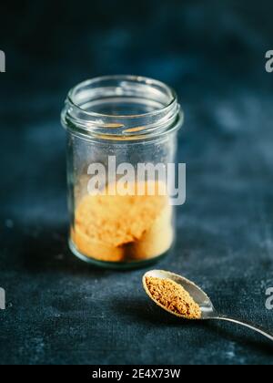 Indische oder pakistanische Masala Pulver in Löffel und Glas. Hausgemachte trockene Curry Garam Masala Mischung Gewürze Mischung auf dunkelgrauen und blauen Hintergrund. Vertikal Stockfoto