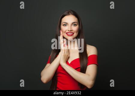 Schöne Brünette Frau mit langen Haaren und roten Maniküre Nägel Lächelnd auf schwarzem Hintergrund Stockfoto