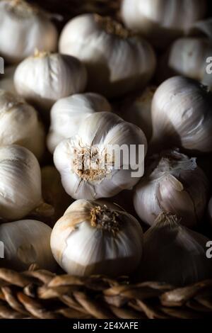 Knoblauchzwiebeln im Korb auf Holzhintergrund. Stockfoto