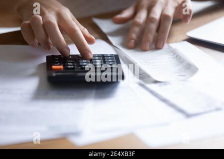 Junge Frau, die Quittung mit dem Rechner hält, um die Zahlungssumme zu überprüfen Stockfoto