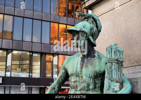 Alte Bronzeskulptur einer männlichen Allegorie des Bismarck-Denkmals in der Düsseldorfer Innenstadt, enthüllt 1899. Modernes Gebäude im Hintergrund. Stockfoto