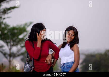 Junge schöne afrikanische Damen bei einem Spaziergang in einem Garten Und freundliche Gespräche führen Stockfoto