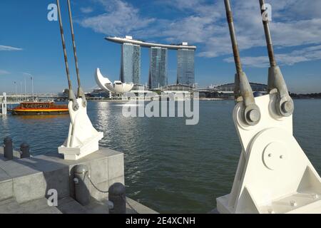 Blick von Esplanade, Singapur, über Marina Bay zum Wahrzeichen Marina Bay Sands Hotel und ein Ausflugsboot, das an einem angedockt ist Stockfoto
