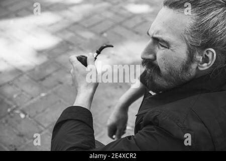 Bärtiger Mann mit Rauchpfeife, schwarz-weißes Profilportrait mit selektivem Fokus Stockfoto