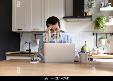 Nachdenkliche junge männliche Freiberufler mit Laptop Denken auf schwierige Problem Stockfoto