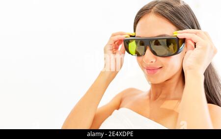 Junge Frau setzt auf Schutzbrille für Lasertherapie in Das Kosmetikstudio Stockfoto