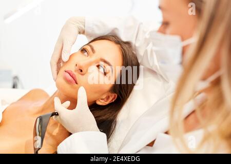 Arzt, der den Patienten über ein Facelift in der Schönheitsklinik berät Stockfoto