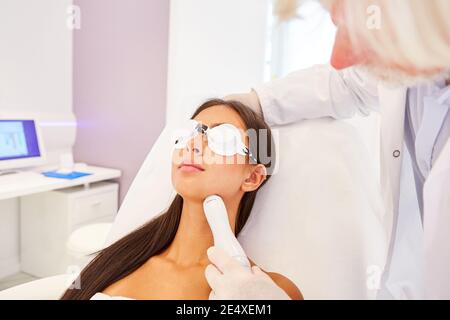 Junge Frau erhält Lasertherapie auf ihrem Hals für die Haut Erneuerung beim Dermatologen Stockfoto