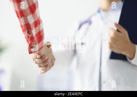 Arzt hält Zwischenablage schüttelt die Hände mit dem Patienten Stockfoto