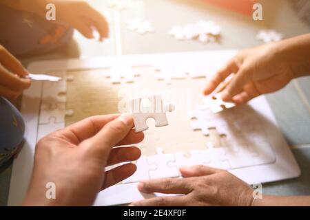 Hand des Vaters und kleine Mädchen spielen Puzzle für Familienkonzept geringe Schärfentiefe Fokus auf Hände wählen Mit Sonneneinstrahlung beeinflussen Stockfoto