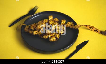 Ansicht der Bandmessung auf einer schwarzen Platte, die aussieht wie Food Pasta.Diet Konzept gesunde Lebensweise Stockfoto