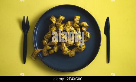 Draufsicht des Maßbands auf einer schwarzen Platte Wie Lebensmittel Pasta.Diet Konzept gesunde Lebensweise Stockfoto