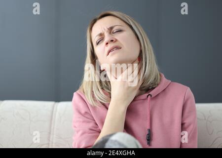 Frau mit geschlossenen Augen hält ihre Hand an ihren Hals Stockfoto