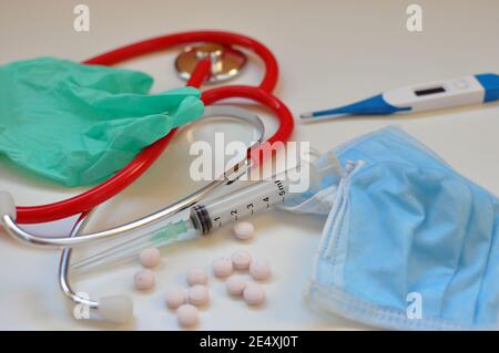 Medizinische Konzeptausrüstung: Medizin Stethoskop und Pillen, Spritze, OP-Handschuh, Digitalthermometer auf weißem Hintergrund. Corona-Virus-Impfung. Stockfoto