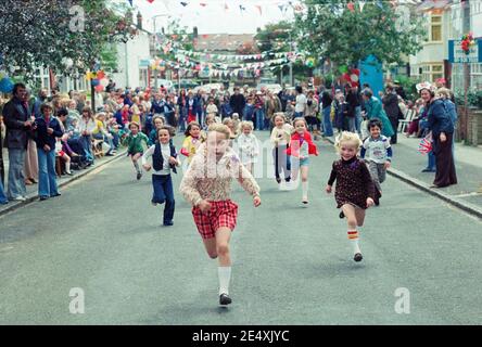 Queens Silver Jubilee 1977 Street Party mit Kindern Rennen in der Straße mit Bunting und Ballons. Evanston Avenue, Highams Park London. Das Silberjubiläum von Elisabeth II. War der 25.. Jahrestag des Beitritts von Königin Elizabeth II. Zu den Thronen des Vereinigten Königreichs Stockfoto