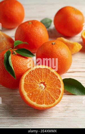 Reife Mandarinen mit Blättern auf weißen Holzbrettern, eine rustikale vertikale Zitruskomposition reich an Vitamin C Stockfoto