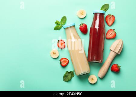 Flaschen mit Erdbeer- und Bananensaft auf einem Minzhintergrund, frische Fruchtsafts in Flaschen, ein gesundes Getränkepaar Stockfoto