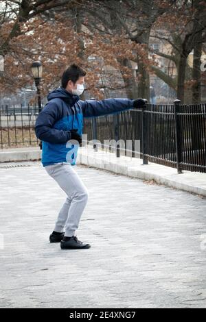 An einem kalten Wintermorgen macht ein Mann Tai Chi Übungen in einem Park in Queens, New York City. Stockfoto