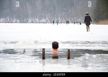 Junge oder Mann Baden und Schwimmen im kalten Wasser eines Sees oder Flusses, Kalttherapie, Eis schwimmen mit Wald oder Park auf dem Hintergrund Stockfoto