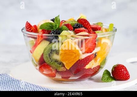 Gesunder frischer Obstsalat in einer Schüssel auf grauem Hintergrund. Stockfoto