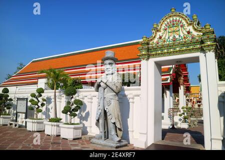 Chinesische Schutzstatue, die vor Jahrhunderten als Ballaststeine auf Schiffen verwendet wurde, neben dem prunkvollen Tor des buddhistischen Tempels Wat Pho, Altstadt von Bangkok, Thailand Stockfoto