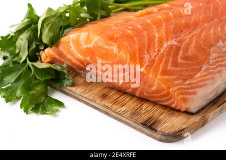 Rohes Lachsfilet und Petersilie auf Schneidebrett isoliert auf Weißer Hintergrund Stockfoto
