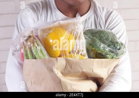 Junger Mann trägt Gemüse für Online-Lieferung. Stockfoto