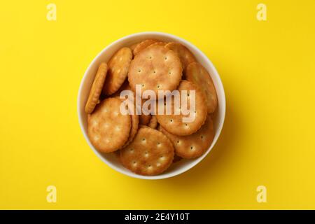 Holzschale mit leckeren Kekscrackern auf einem gelben Hintergrund, ein helles fröhliches knuspriges Knabbergebäck Stockfoto