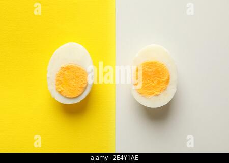 Ein einzelnes gekochtes Ei auf einem zweifarbigem Hintergrund in Top-Down-Ansicht, eine minimalistische Farbblockkomposition Stockfoto