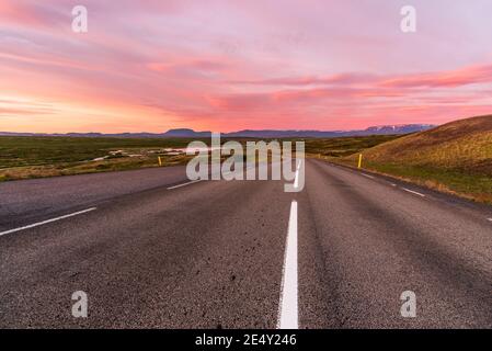 Majestätischer Sommeruntergang über einer kurvenreichen Bergstraße, die hinunter führt Zu einem Tal Stockfoto