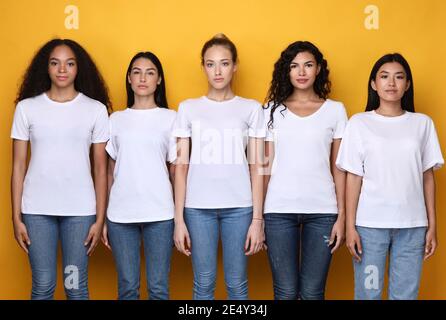 Fünf Ernsthafte Multiethnische Frauen Stehen Zusammen Über Gelbem Hintergrund Stockfoto