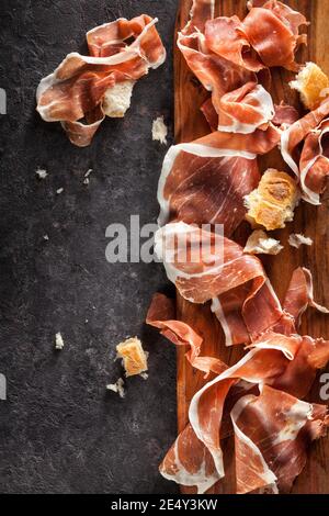 Scheiben Prosciutto auf dunklem Hintergrund. Draufsicht. Stockfoto