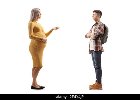 In voller Länge Profilaufnahme einer schwangeren Frau in einem Gelbes Kleid im Gespräch mit einem männlichen Schüler mit einer Rucksack isoliert auf weißem Hintergrund Stockfoto