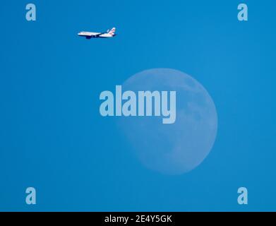 London, Großbritannien. 25. Januar 2021. Der Flugverkehr auf dem Weg nach London Heathrow passiert bei klarem und kaltem Nachmittagswetter den zunehmenden Gibbous Moon. Quelle: Malcolm Park/Alamy Live News. Stockfoto