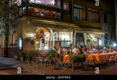 Urlauber speisen im Freien in einer Bar in Malcesine, am Ostufer des Gardasees in der Region Venetien in Italien. Stockfoto