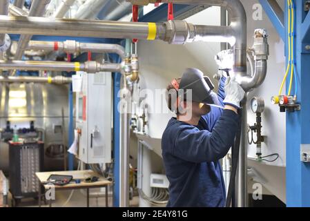 Schweißer arbeitet im Stahlbau und repariert ein Industriewerk Stockfoto