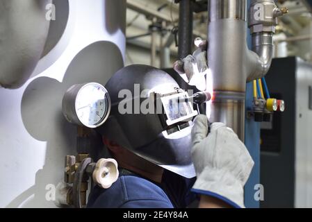 Schweißer arbeitet im Stahlbau und repariert ein Industriewerk Stockfoto