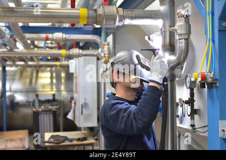 Schweißer arbeitet im Stahlbau und repariert ein Industriewerk Stockfoto