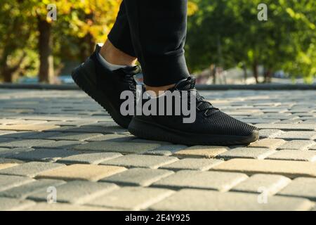 Mann in schwarzen Sneakers und Jogginghosen läuft im Park Stockfoto