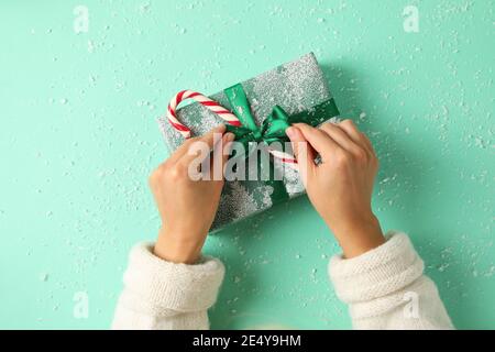 Weibliche Hände öffnen die Geschenkbox auf mintgrün Hintergrund Stockfoto